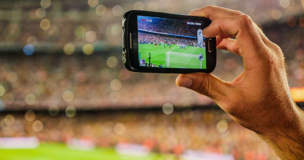 Handheld mobile phone capturing game day for live content capture program in sports.