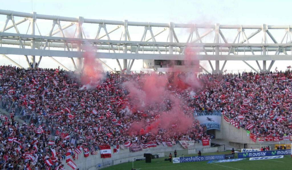 Stadium filled with fans, sponsor signage and red smoke celebrating game day - live content capture program in sports.